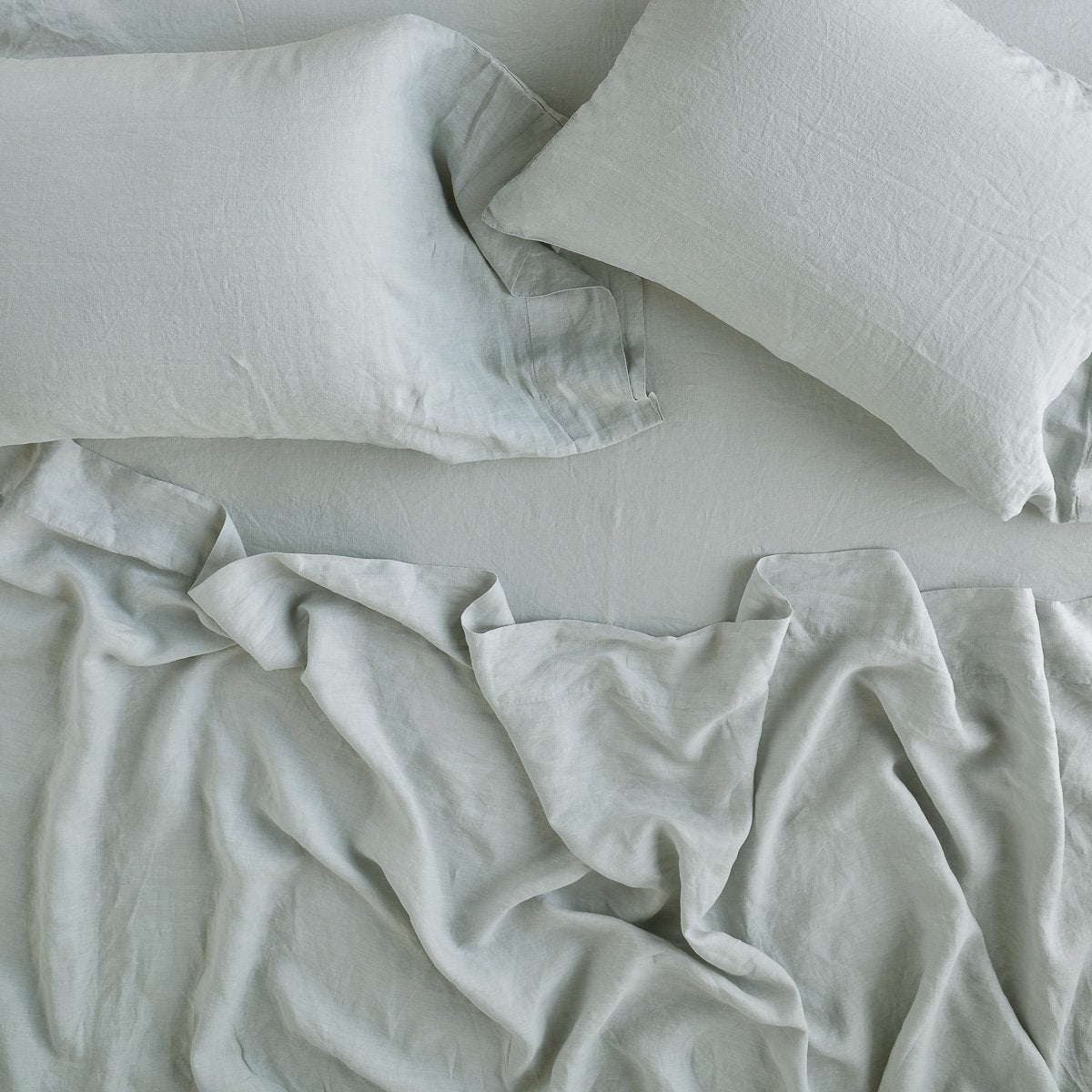 Eucalyptus: sleeping pillows laid flat on rumpled matching sheeting - overhead view.