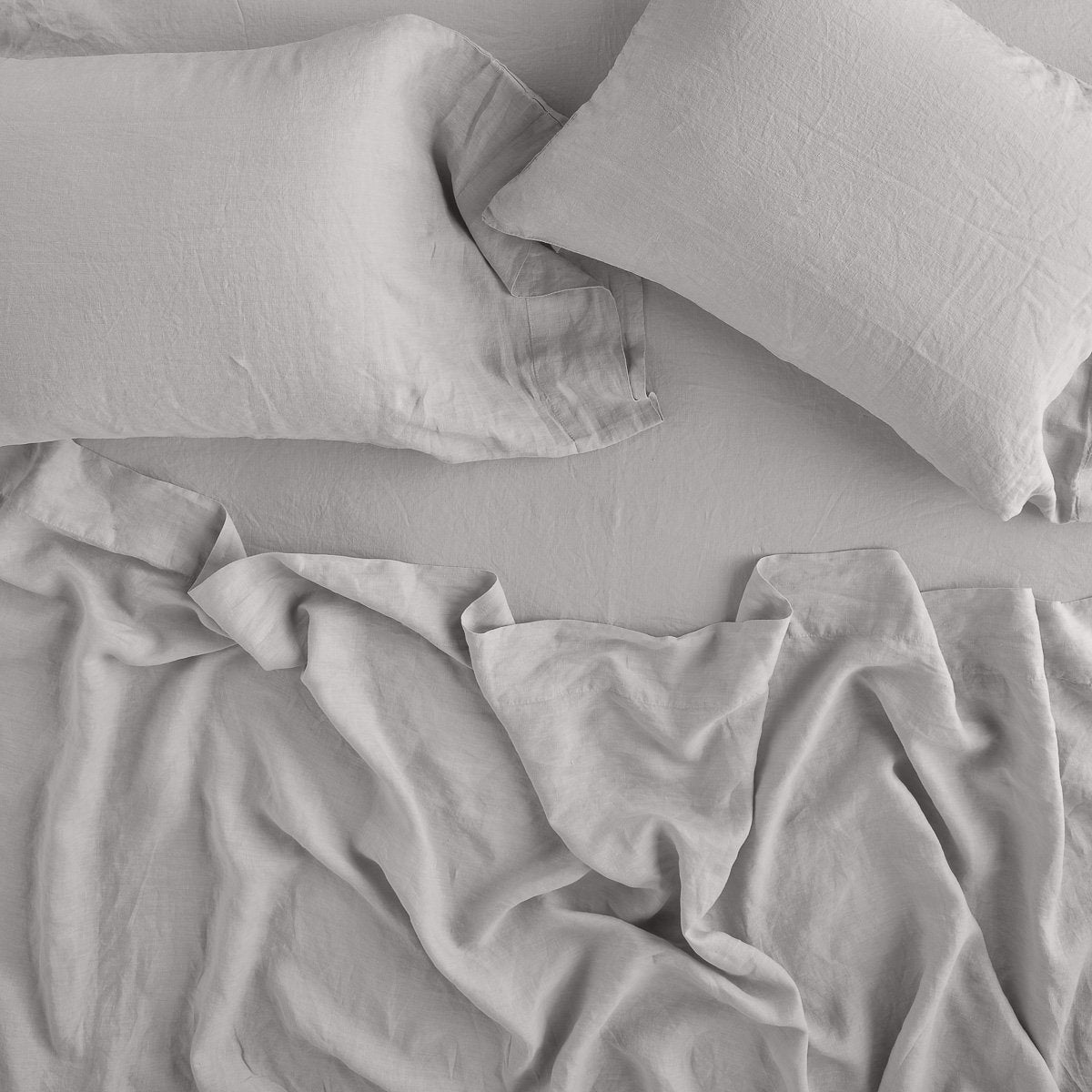 Fog: sleeping pillows laid flat on rumpled matching sheeting - overhead view.