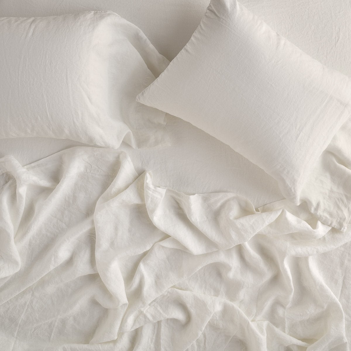 Parchment: sleeping pillows laid flat on rumpled matching sheeting - overhead view.