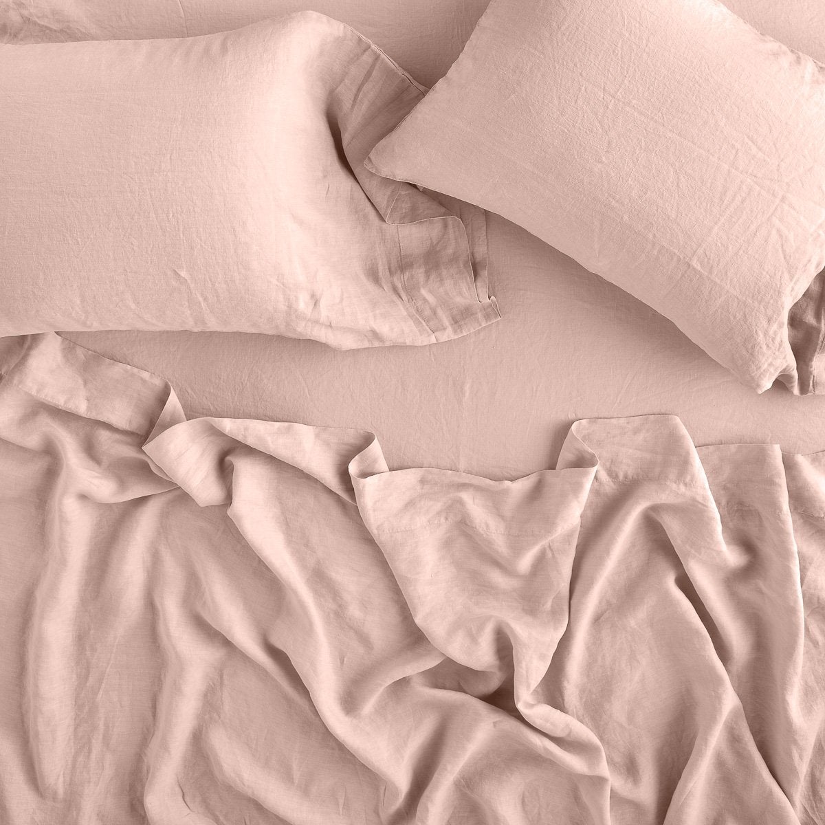 Rouge: sleeping pillows laid flat on rumpled matching sheeting - overhead view.