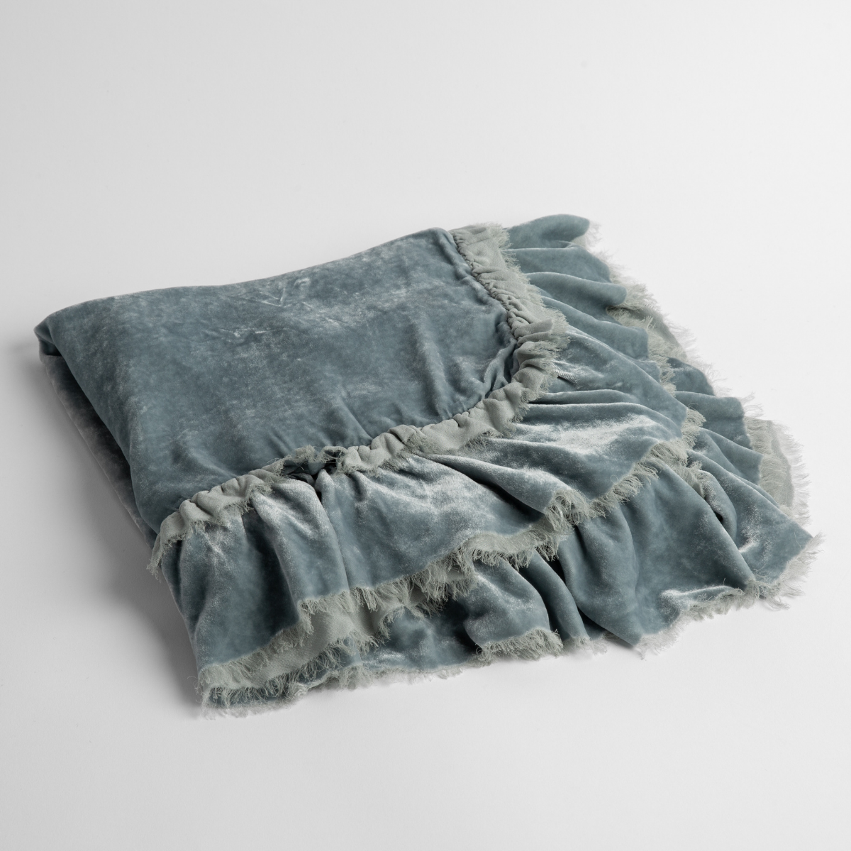 Cloud:  an overhead shot of a folded silk velvet baby blanket with a raw-edged eyelash ruffle detail.
