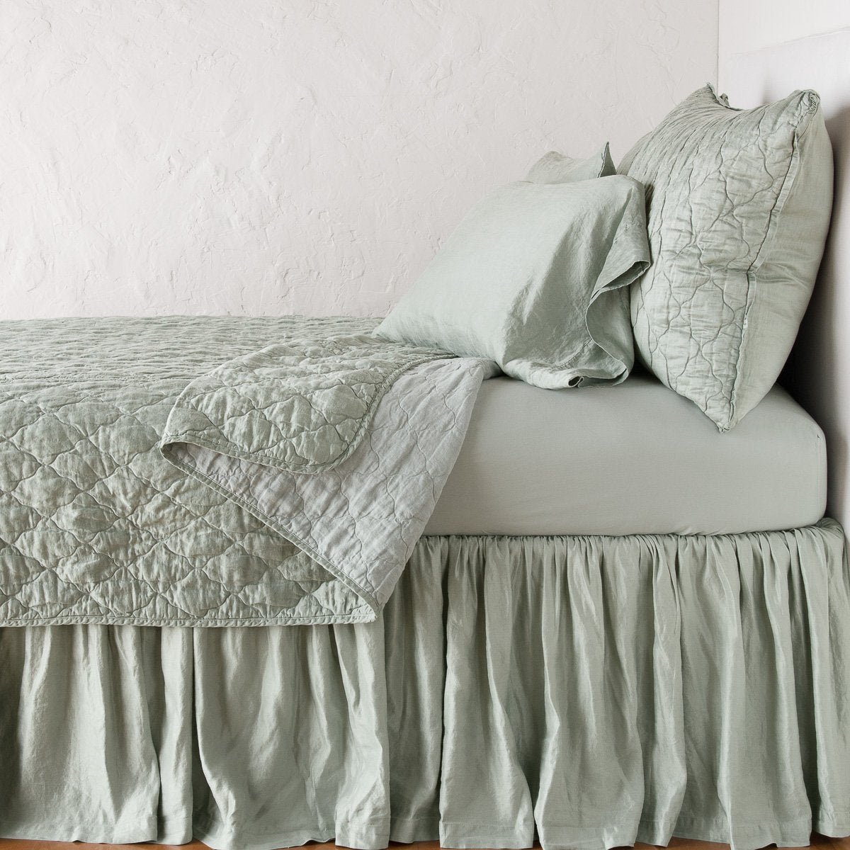 Eucalyptus: shams with a matching coverlet pulled back over monochromatic sheeting - side view.