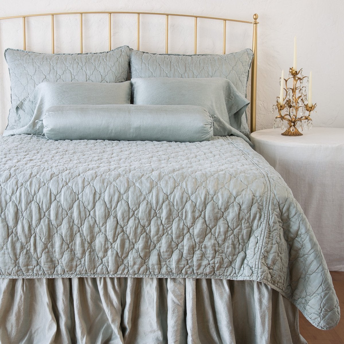 Mineral: shams on a shining, monochromatic bed with matching coverlet - end of bed view.