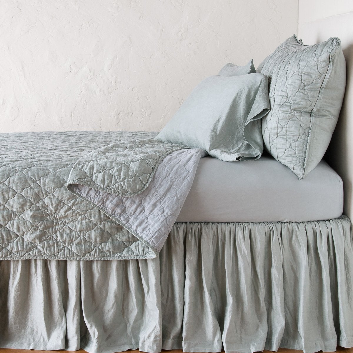Mineral: shams with a matching coverlet pulled back over monochromatic sheeting - side view.