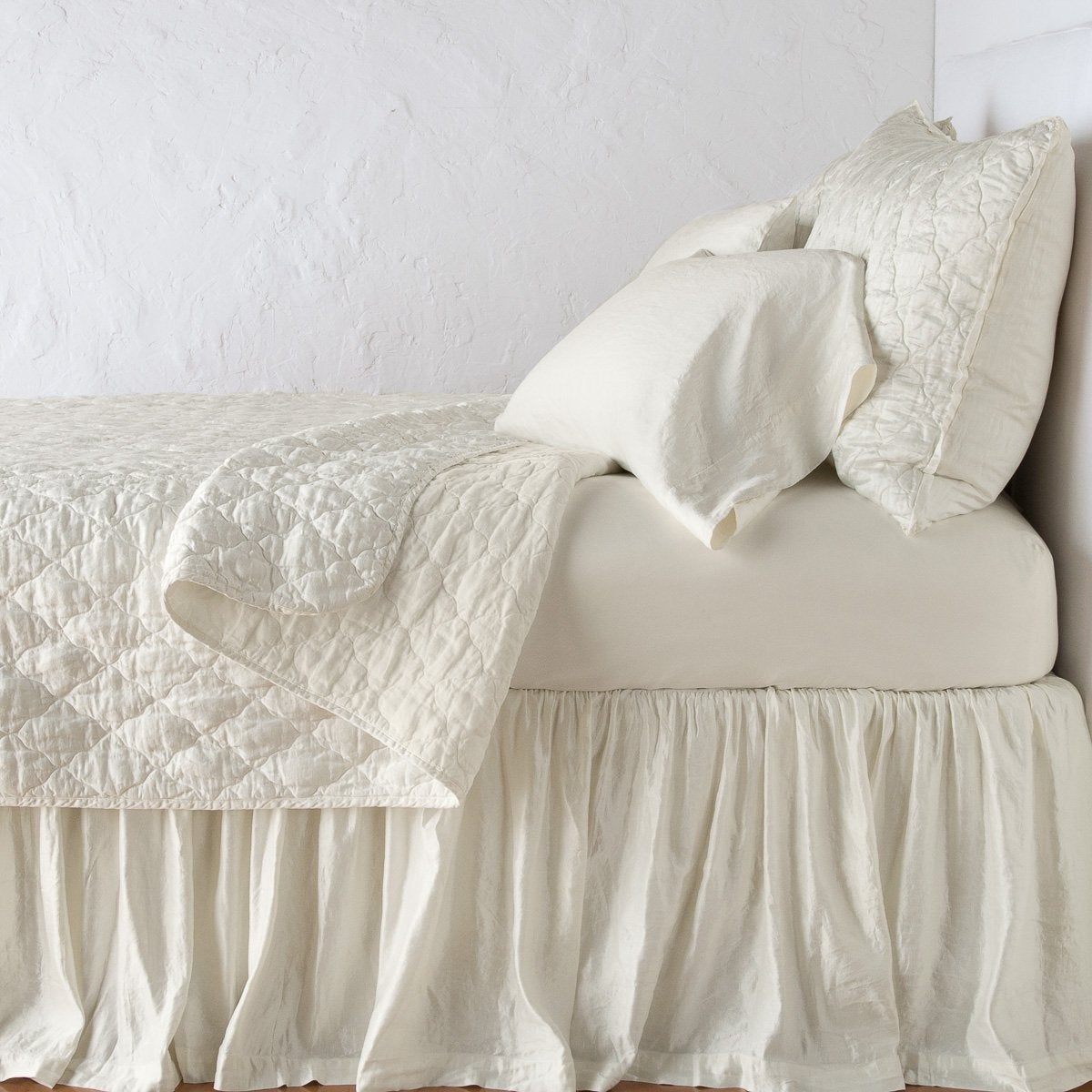 Parchment: shams with a matching coverlet pulled back over monochromatic sheeting - side view.