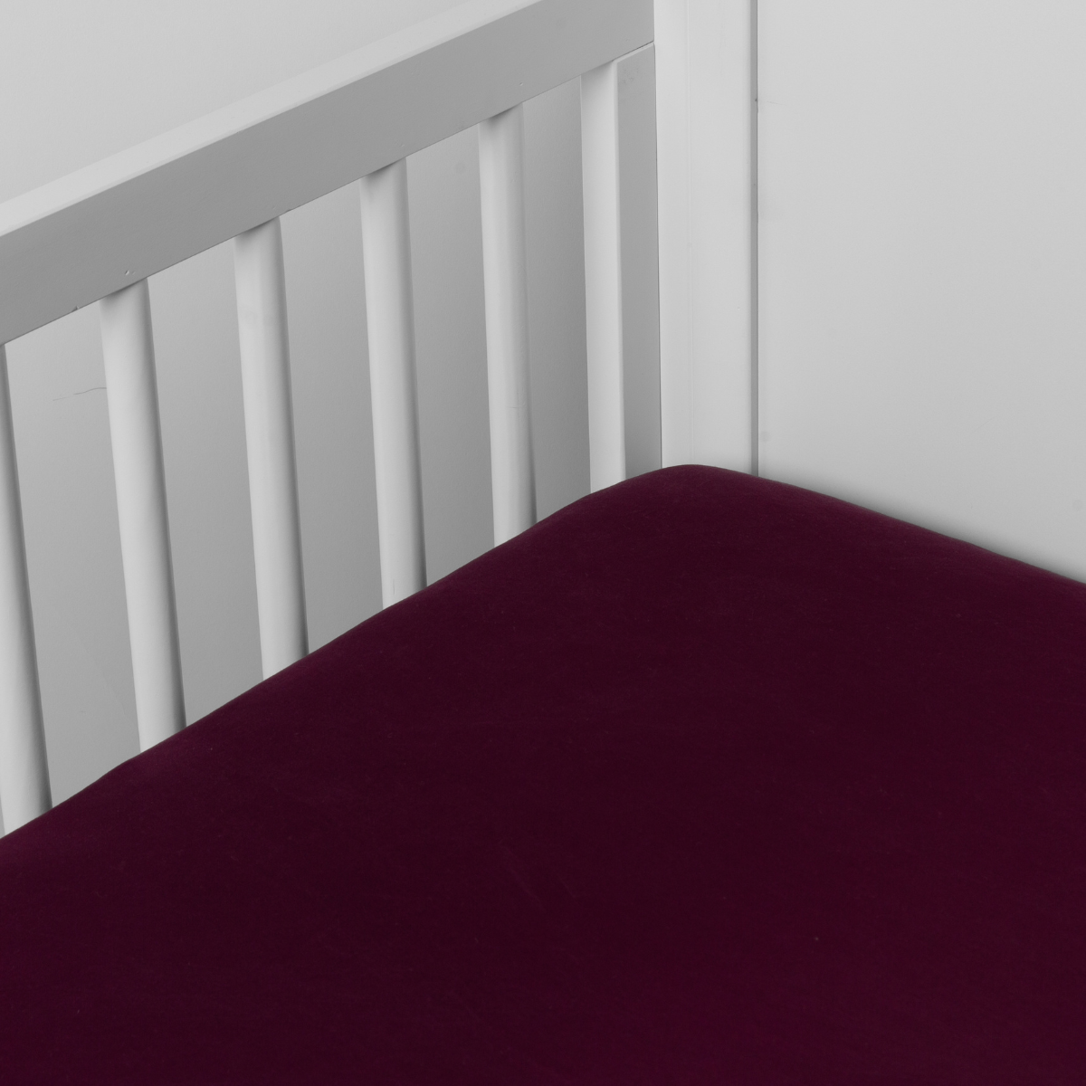 Fig:  crib sheet shown on a mattress shown from overhead into the corner of a crib. 