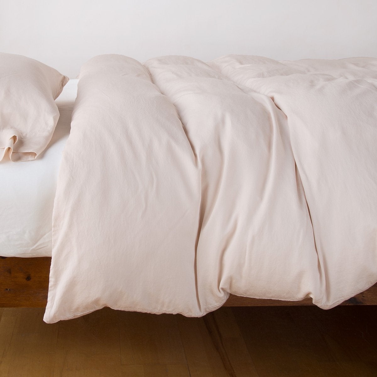 : Madera Luxe duvet cover with matching sleeping pillow and white fitted sheet - pearl, side view.