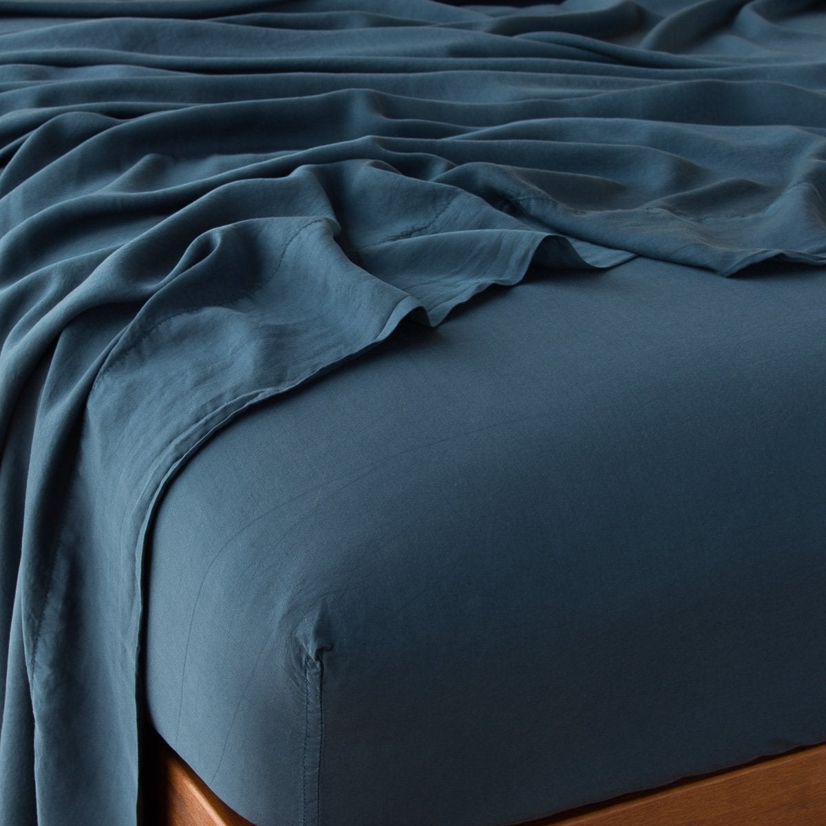 Midnight: fitted sheet with matching rumpled flat sheet - top corner view.