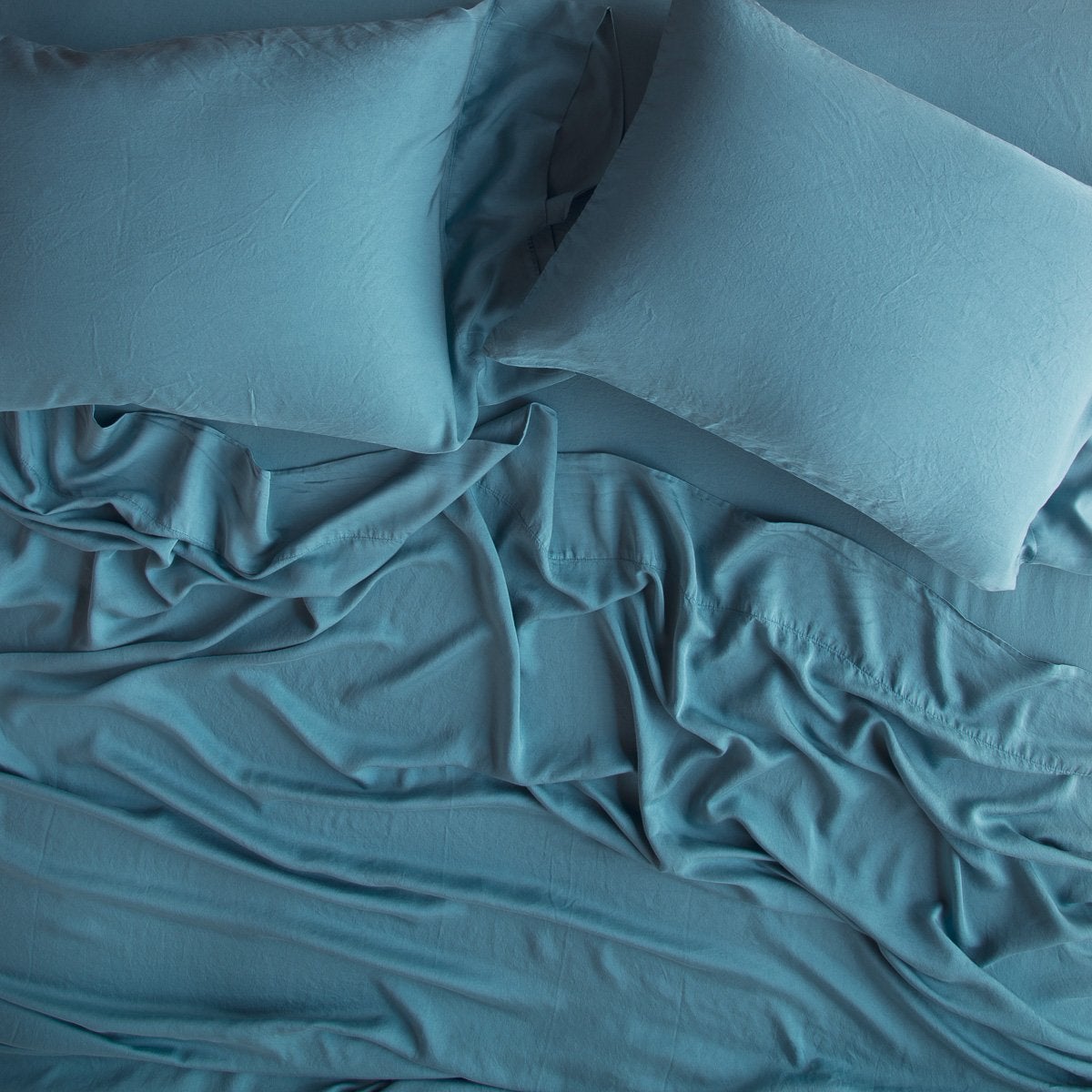 Cenote: sleeping pillows laid flat over rumpled matching sheeting - overhead view.