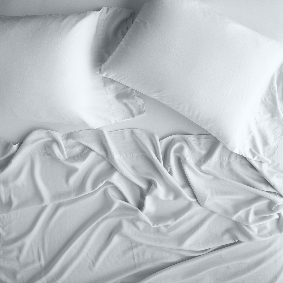 Cloud: sleeping pillows laid flat over rumpled matching sheeting - overhead view.