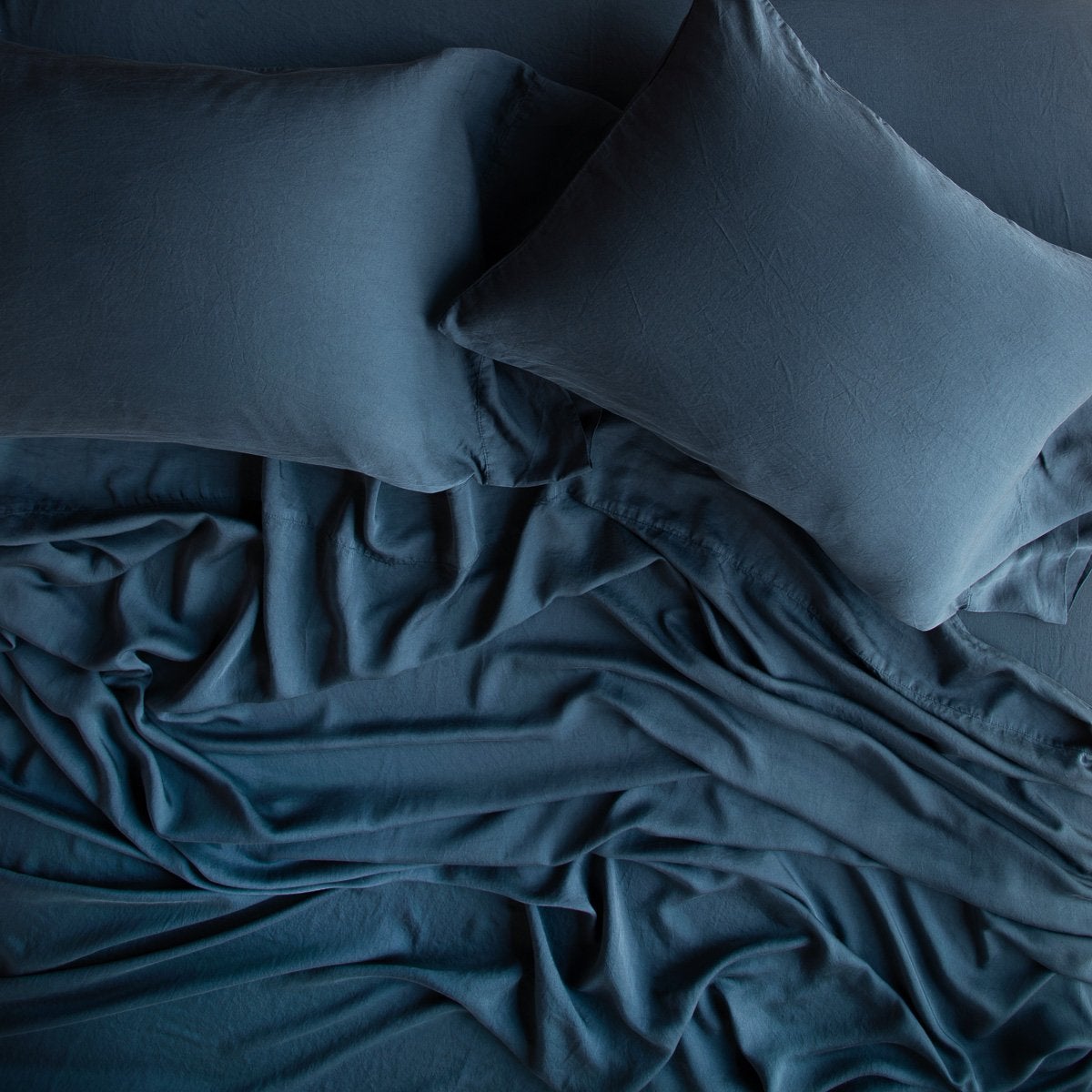 Midnight: sleeping pillows laid flat over rumpled matching sheeting - overhead view.