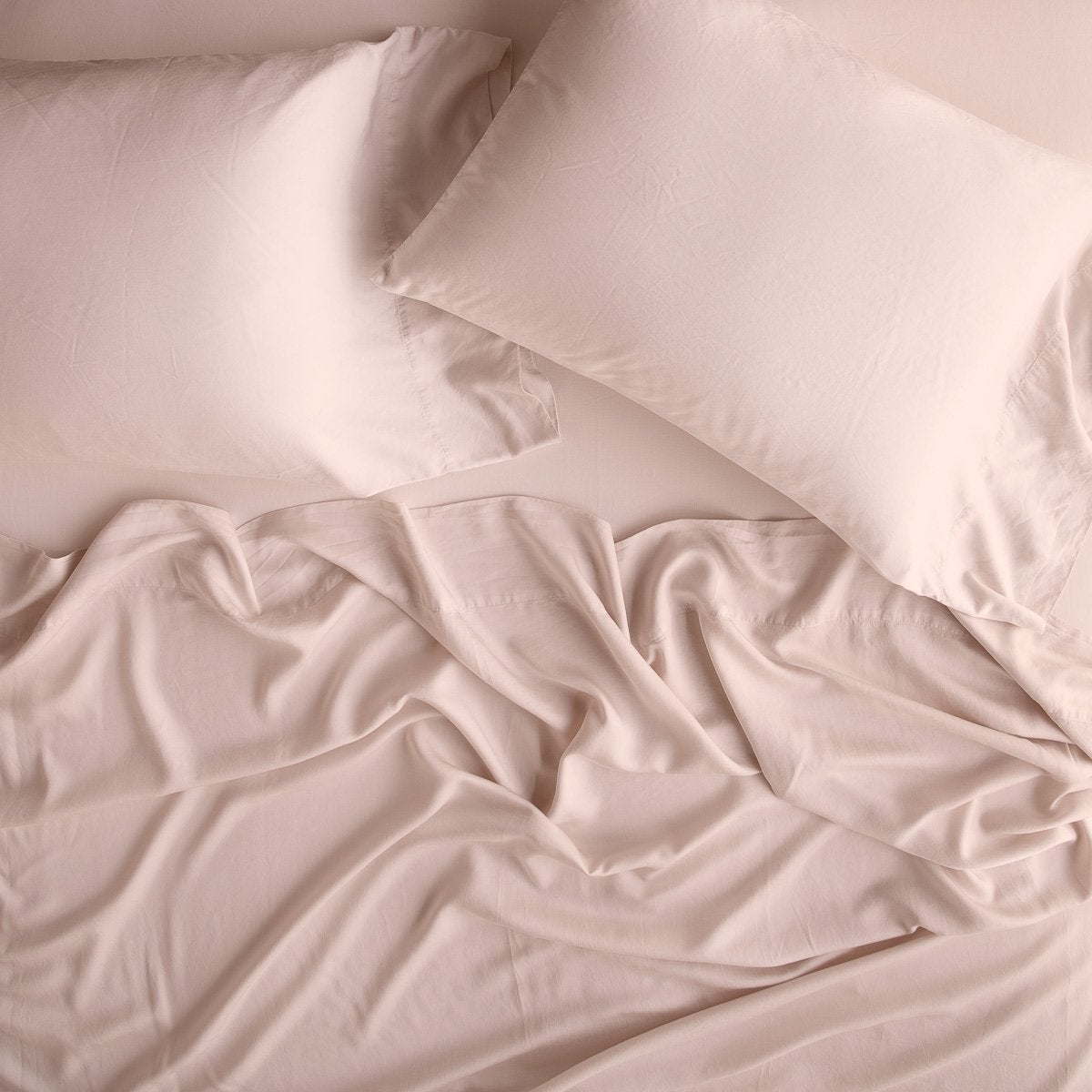 Rouge: sleeping pillows laid flat over rumpled matching sheeting - overhead view.