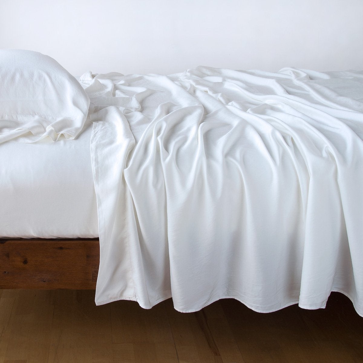 White: sleeping pillow with matching rumpled sheeting - side view.