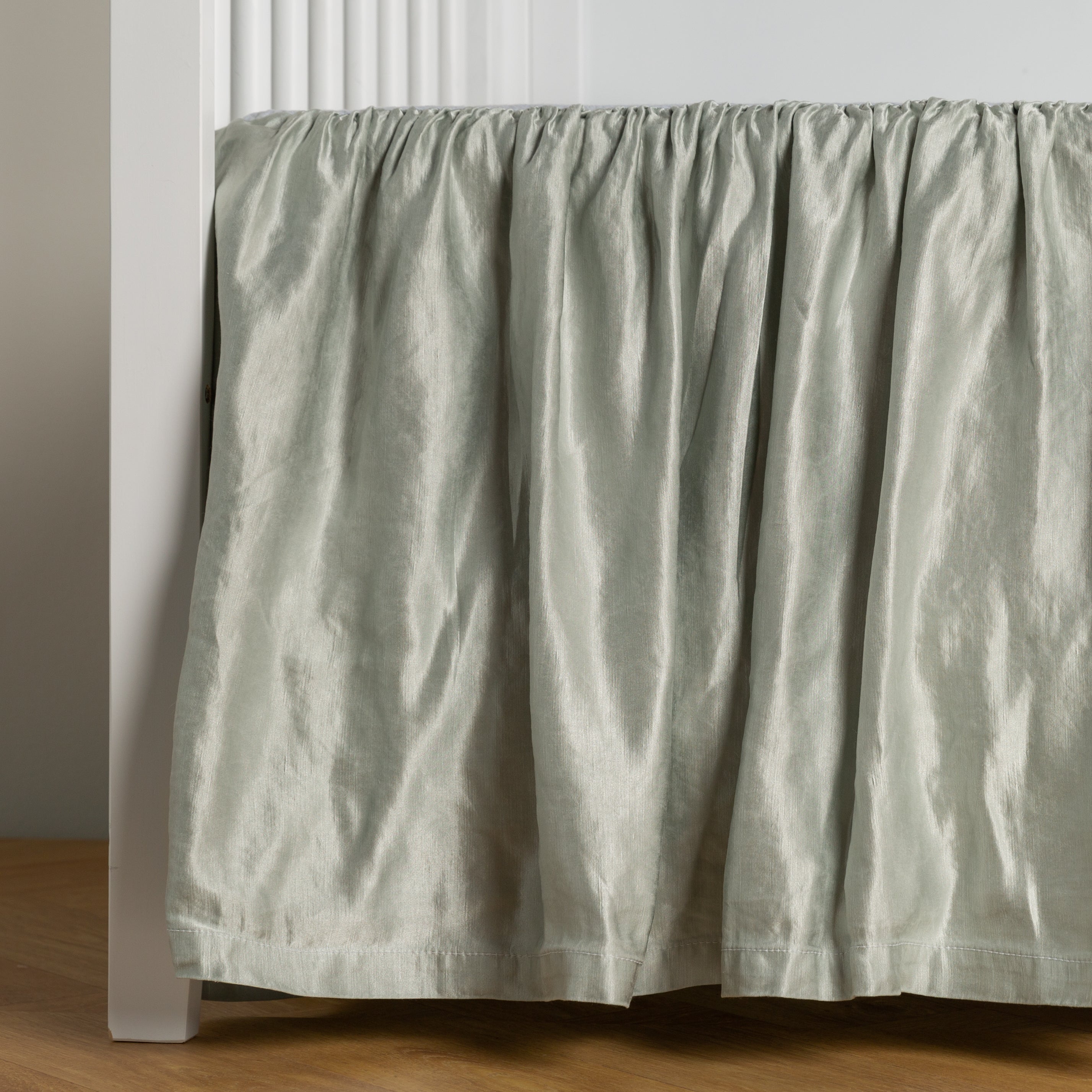 Cloud:  charmeuse crib skirt shown on a white crib against a white wall and medium wood floor. 