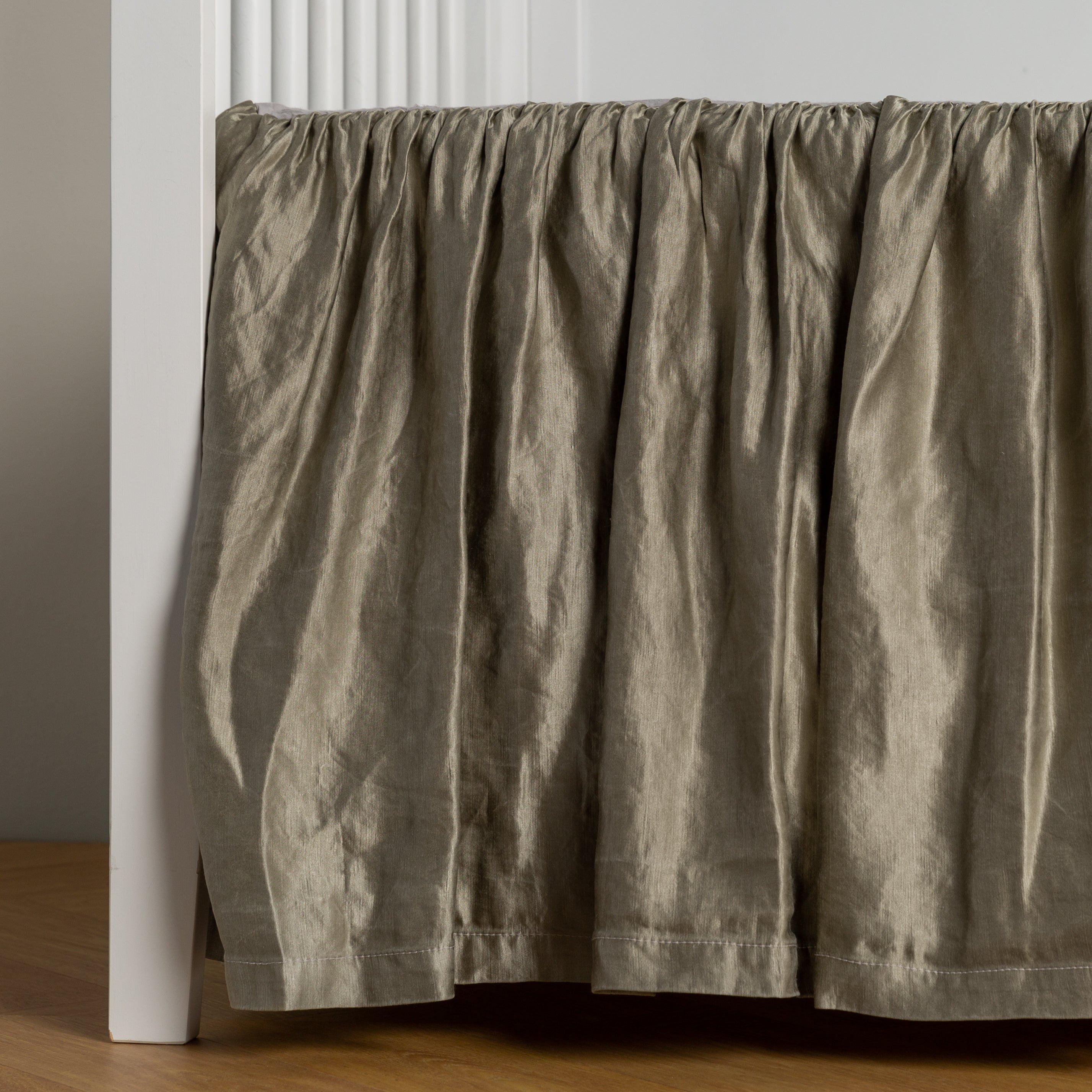 Moonlight:  charmeuse crib skirt shown on a white crib against a white wall and medium wood floor. 
