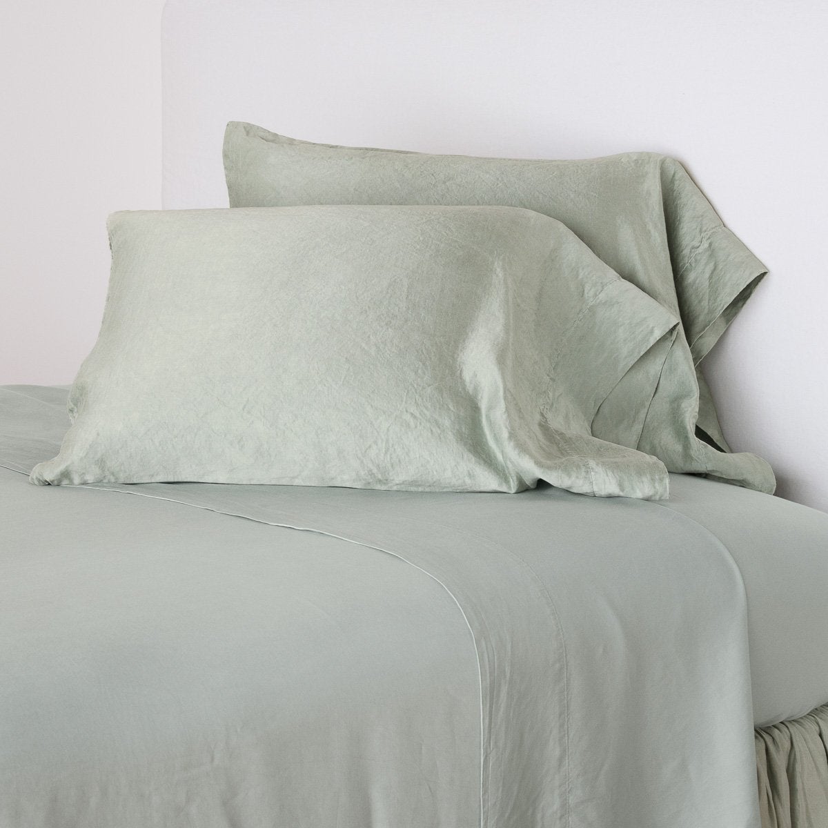 Eucalyptus: sleeping pillows leaning upright against a white wall on monochromatic sheeting - cropped three-quarter angle.