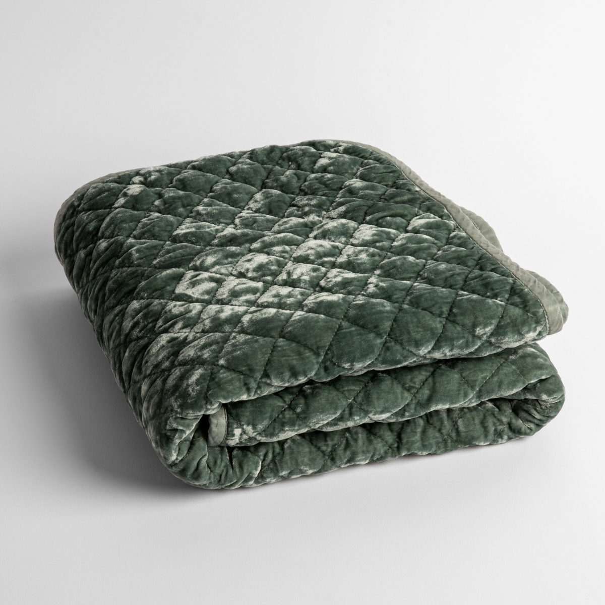 Eucalyptus: a folded quilted silk velvet baby blanket shown from overhead to showcase quilting  pattern and texture. 