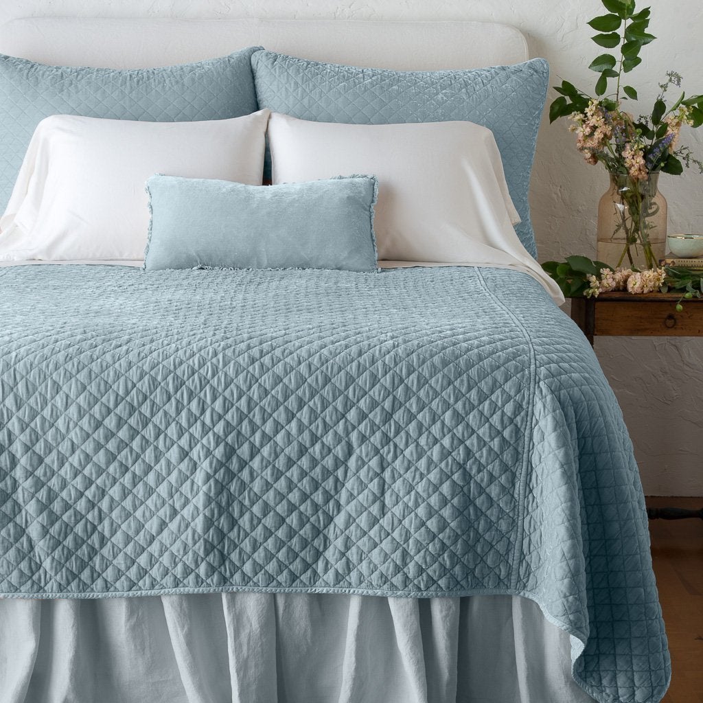 Cloud: shams with matching coverlet on a neatly-made, bed with white sheeting - end of bed view.