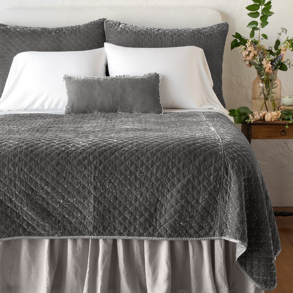 Fog: shams with matching coverlet on a neatly-made, bed with white sheeting - end of bed view.