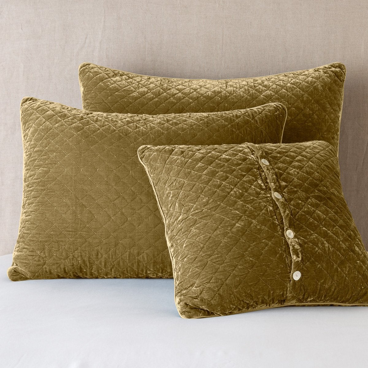 Honeycomb: shams leaning upright against a neutral headboard. One sham is backwards to showcase the shimmering shell button closure.