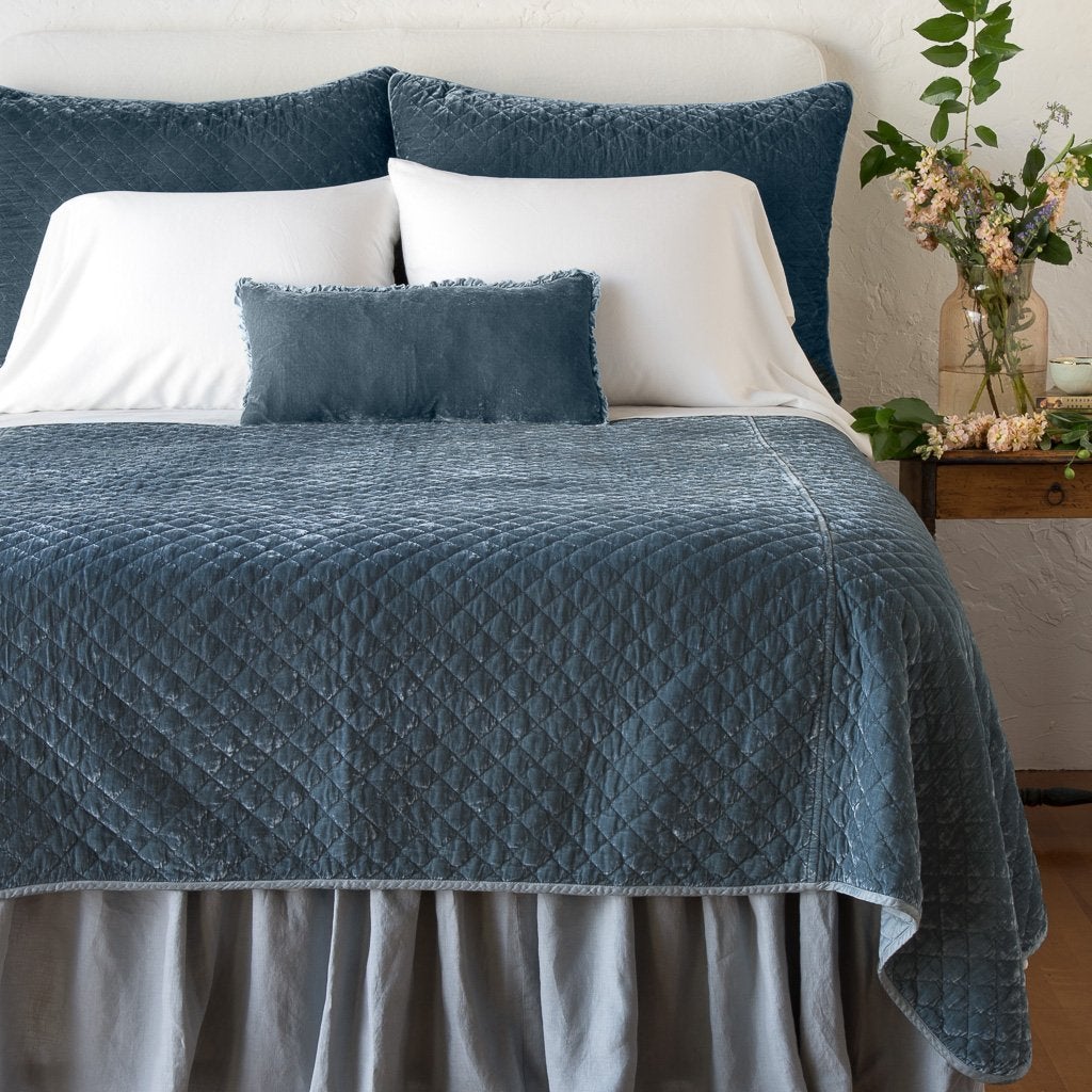 Mineral: shams with matching coverlet on a neatly-made, bed with white sheeting - end of bed view.