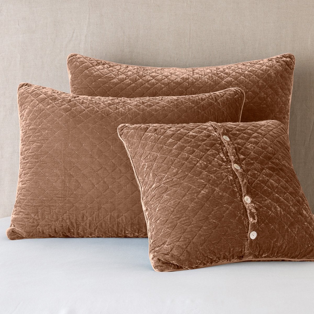 Rouge: shams leaning upright against a neutral headboard. One sham is backwards to showcase the shimmering shell button closure.