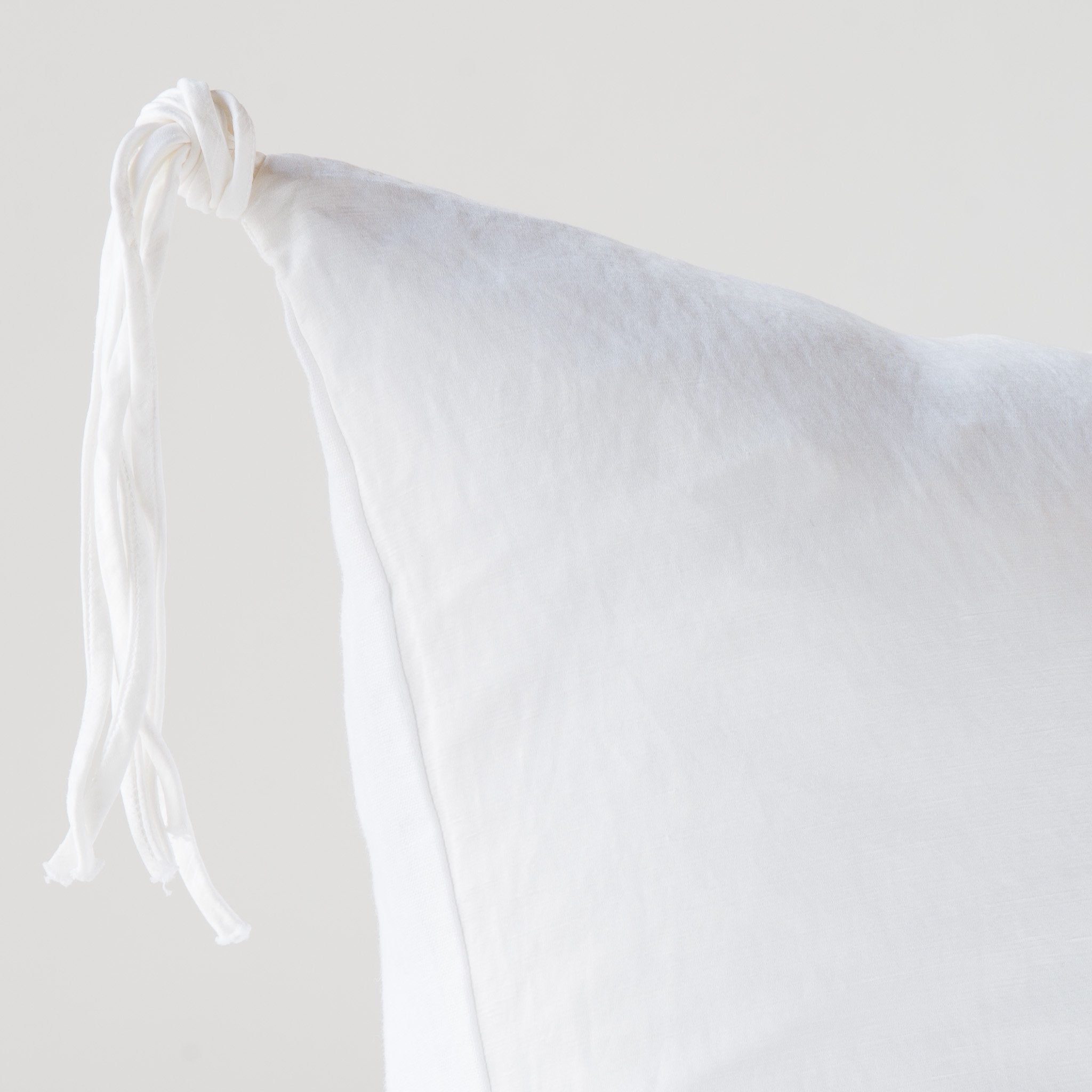 White: Corner detail close-up, highlighting hand-tied charmeuse tassel.
