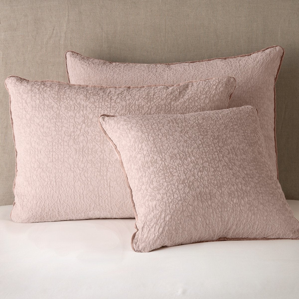 Rouge: Cotton chenille jacquard shams leaning upright against a neutral headboard.
