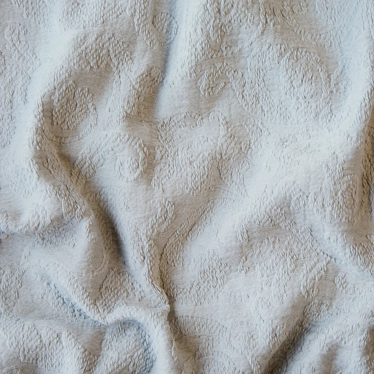 Sterling: A close up of Adele fabric in sterling, a silvery neutral light grey. The fabric is rumpled to show the cotton damask texture.