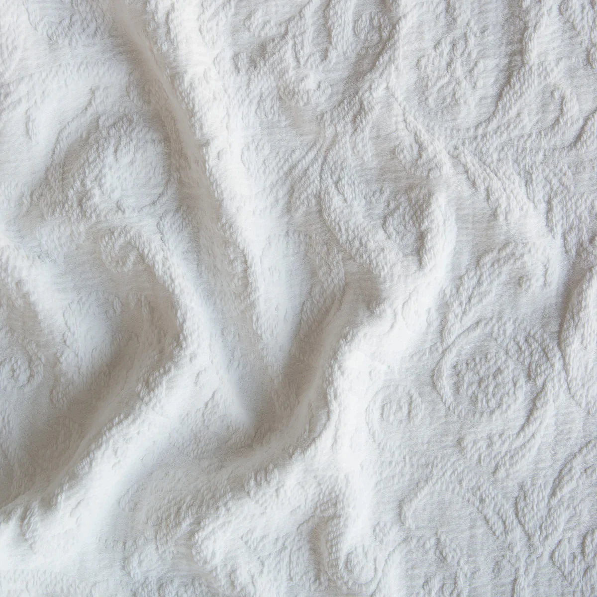 Winter White: A close up of Adele fabric in winter white, softer and warmer in tone than classic white. The fabric is rumpled to show the cotton damask texture.