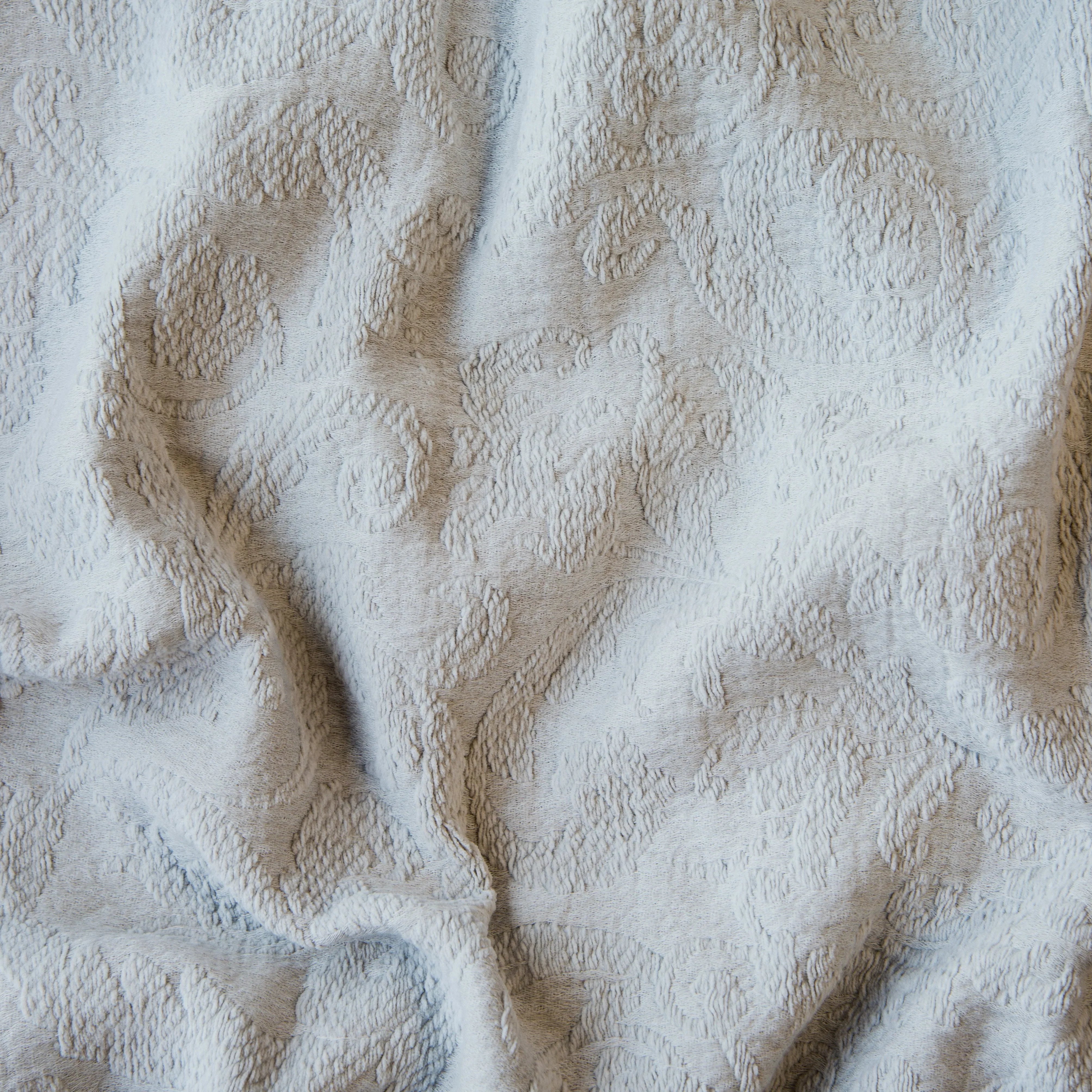 Sterling: A close up of Adele fabric in sterling, a silvery neutral light grey. The fabric is rumpled to show the cotton damask texture.