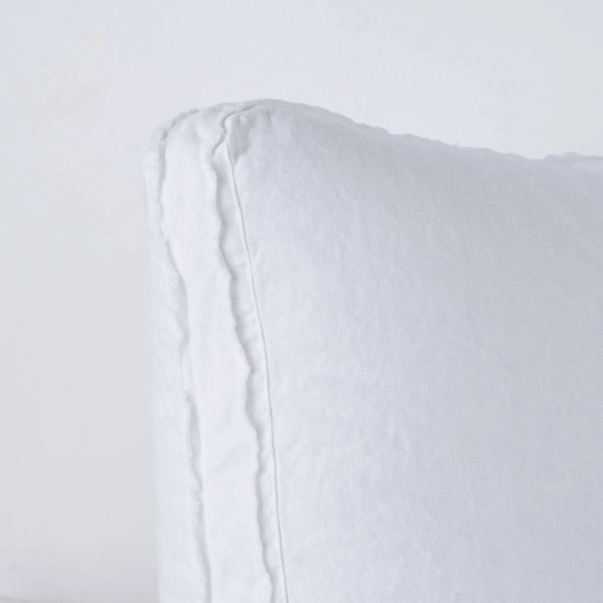 White: Close-up angle of the corner of an Austin sham, highlighting the raw edge trim on either side of the gusset.