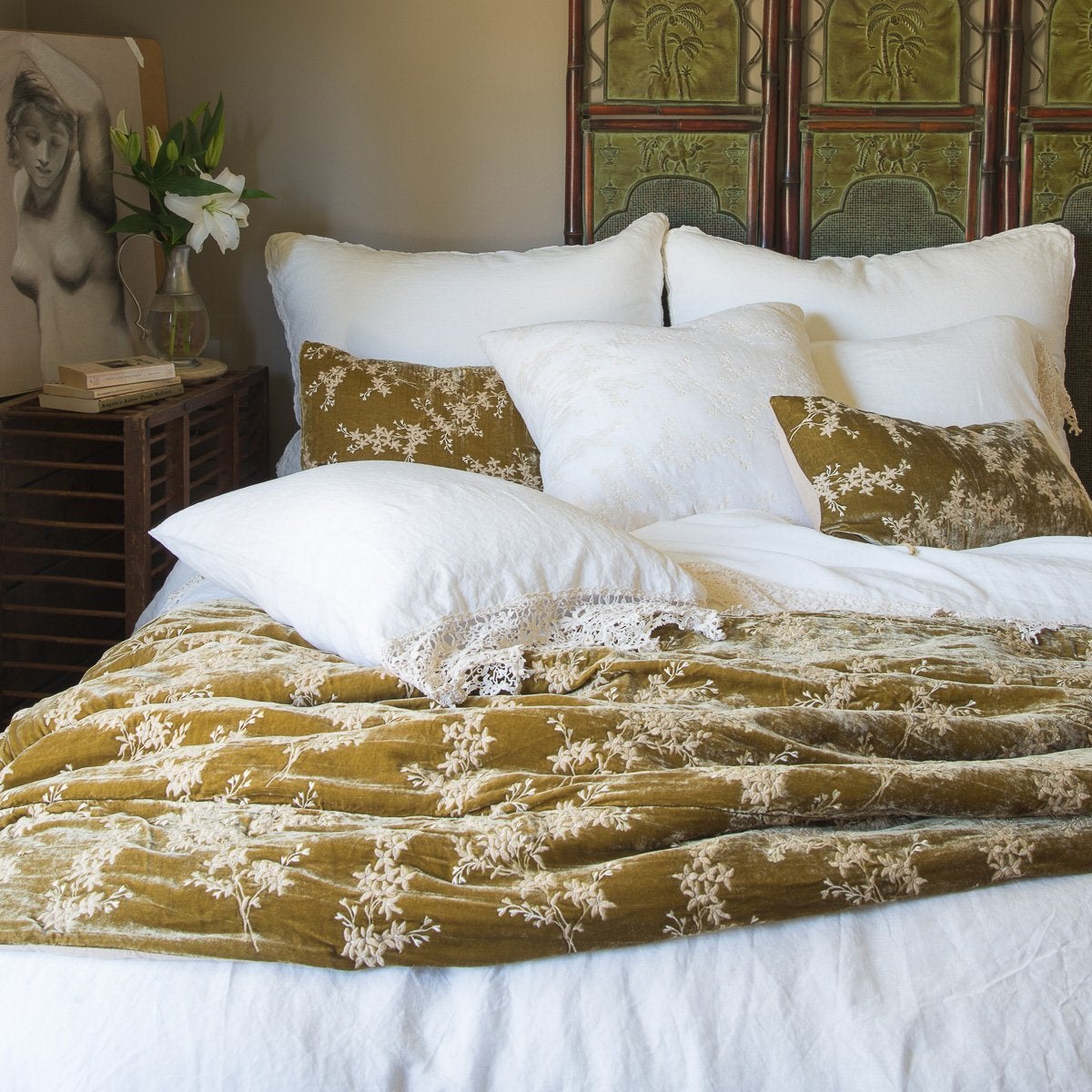 : Linen duvet cover in white layered under white frida lace sheeting and sleeping pillows and rich honeycomb silk velvet accessory pieces - end of bed view.