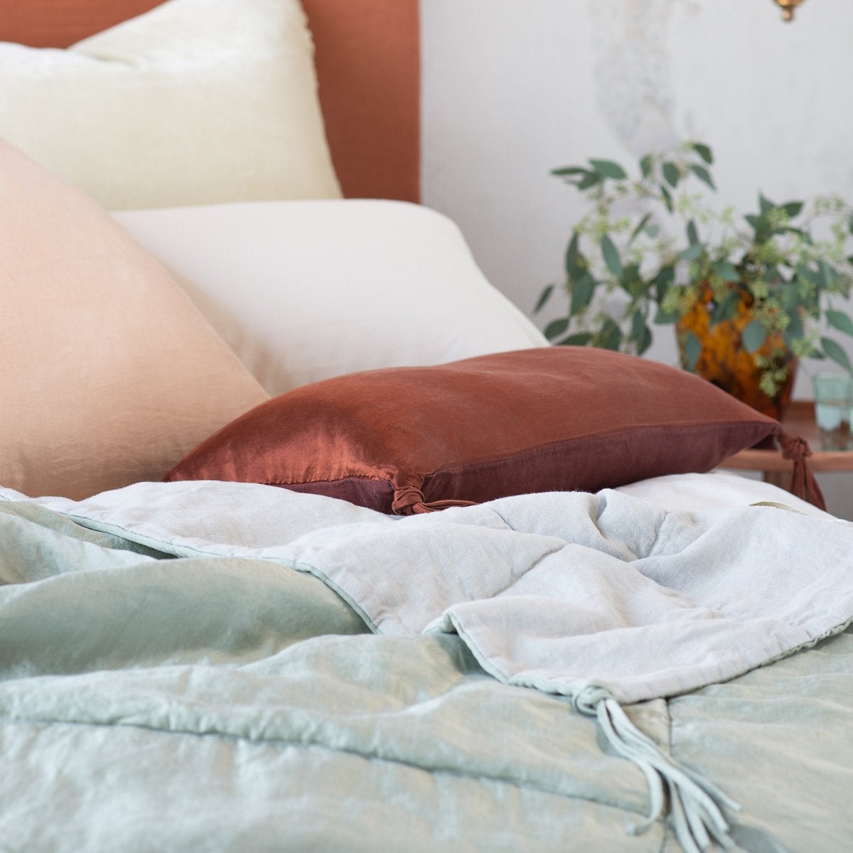 : Close-up of rumpled Taline throw blanket in cloud, with cream, pale pink, and mahogany accents.