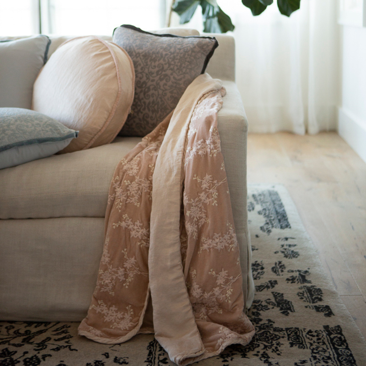 : embroidered silk velvet blanket with charmeuse trim and back in Pearl draped at end of couch. 