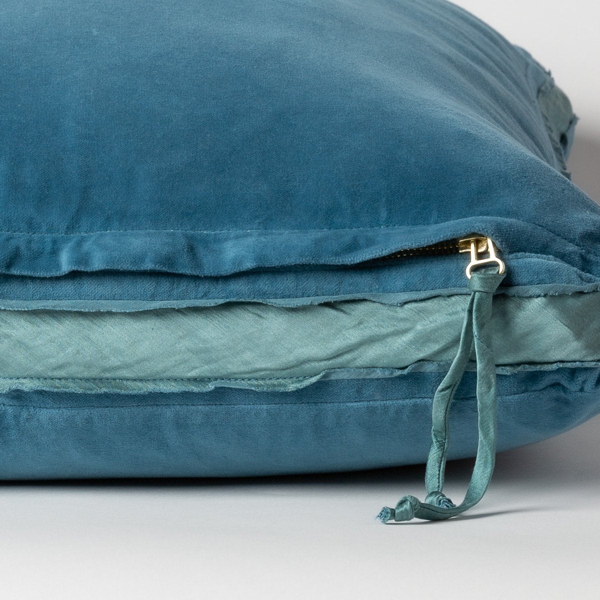 Cenote: Close-up of charmeuse gusset, raw-edge trim, and brass zipper detail on Harlow pillow - side view.