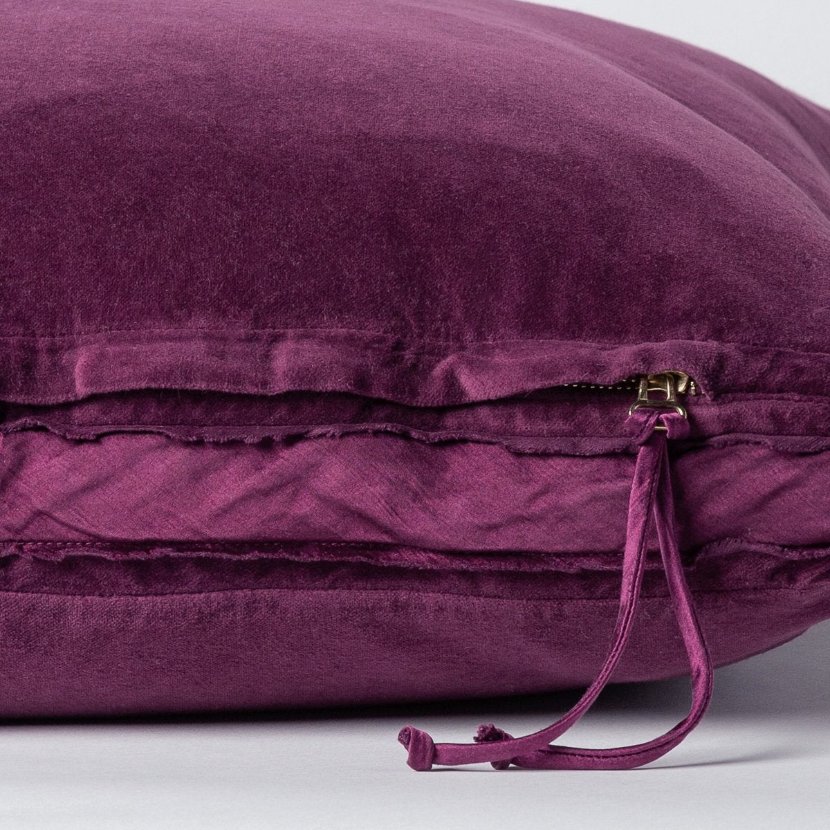 Fig: Close-up of charmeuse gusset, raw-edge trim, and brass zipper detail on Harlow pillow - side view.