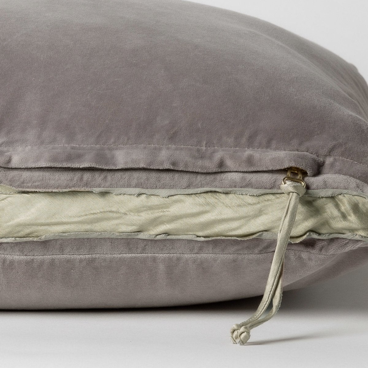 Fog: Close-up of charmeuse gusset, raw-edge trim, and brass zipper detail on Harlow pillow - side view.