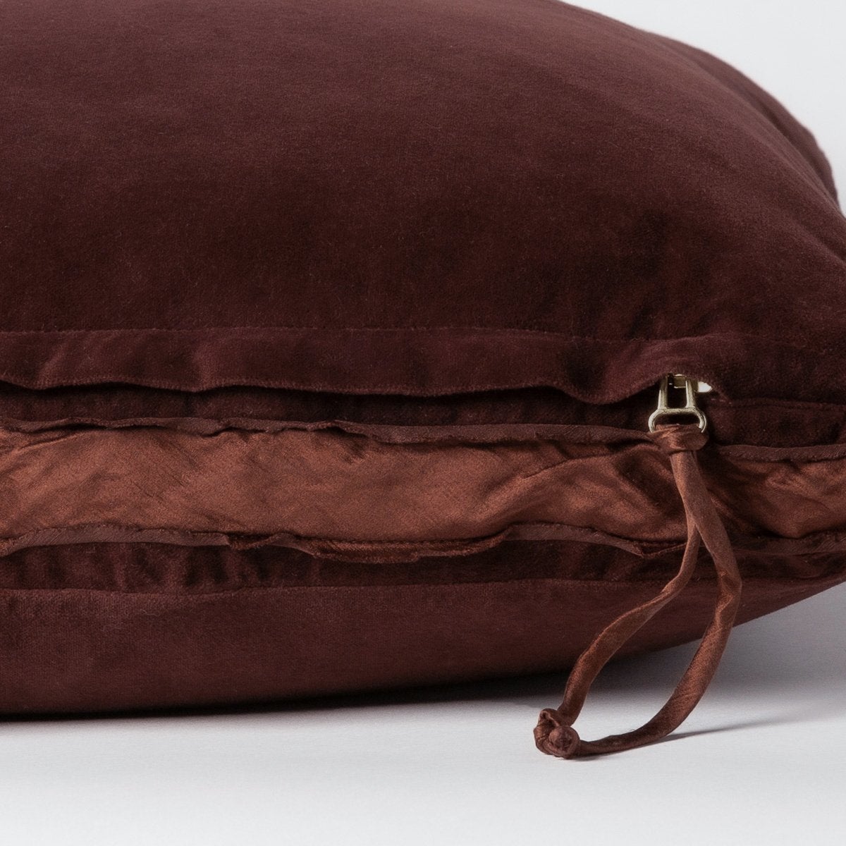 Mahogany: Close-up of charmeuse gusset, raw-edge trim, and brass zipper detail on Harlow pillow - side view.
