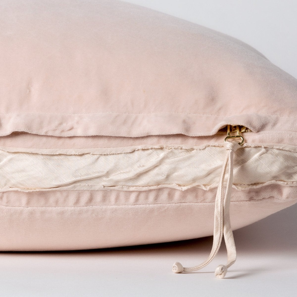Pearl: Close-up of charmeuse gusset, raw-edge trim, and brass zipper detail on Harlow pillow - side view.