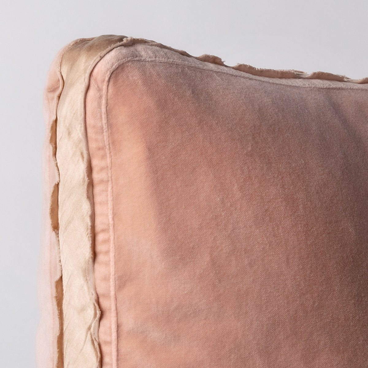 Rouge: Corner detail close-up of cotton velvet 24 by 24 pillow, showcasing charmeuse gusset and raw edge trim.