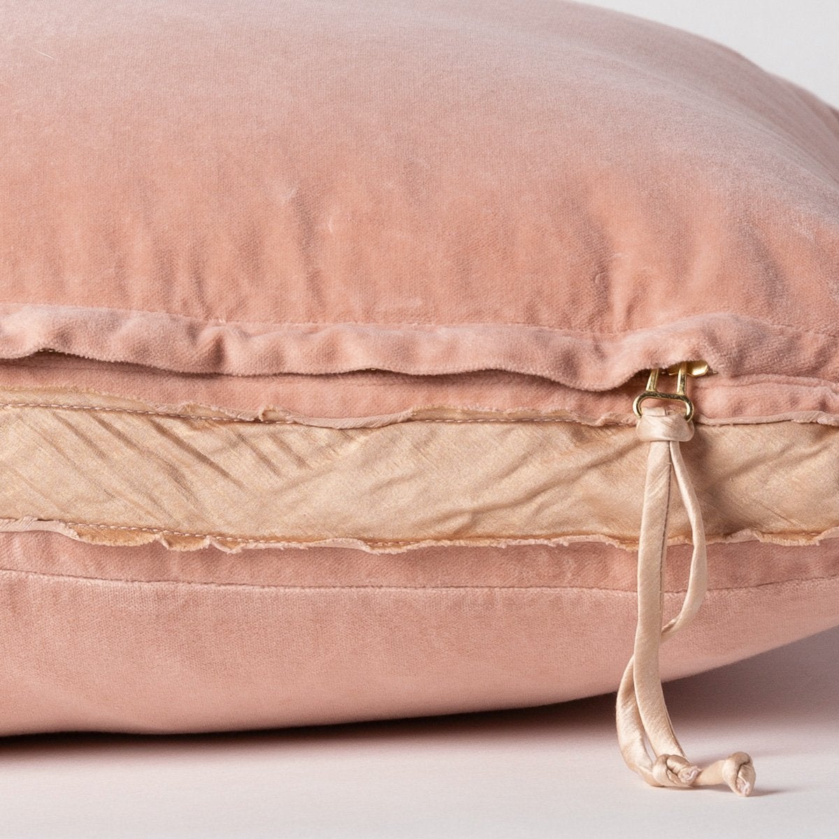 Rouge: Close-up of charmeuse gusset, raw-edge trim, and brass zipper detail on Harlow pillow - side view.
