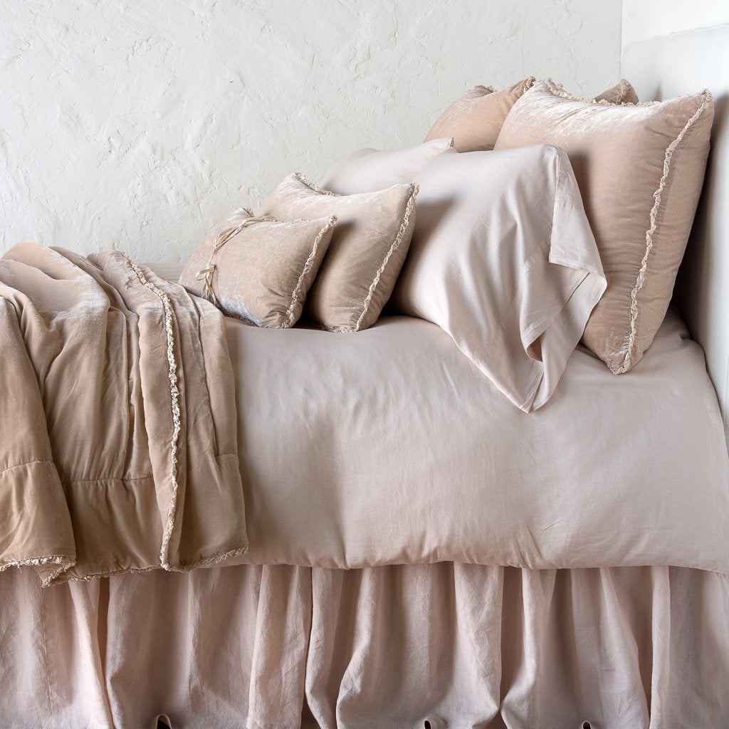 Pearl: Silk velvet lumbar pillow with petite ruffle on a monochromatic, neatly made bed with matching accessory pieces - side view.