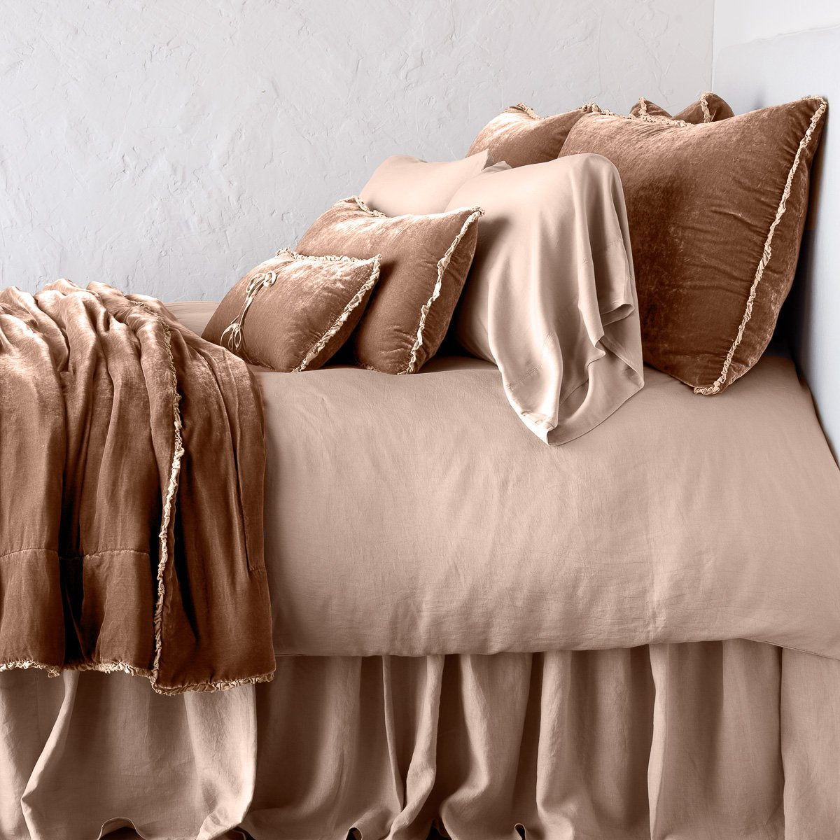Rouge: Silk velvet throw blanket with petite ruffle, draped across a monochromatic bed - side view.