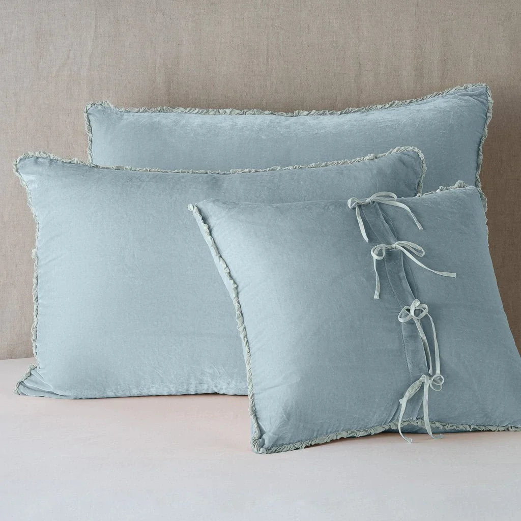 Cloud: Silk velvet  shams with a petite ruffle leaning upright against a neutral headboard. The front sham is backwards, showcasing the charmeuse tie closures.