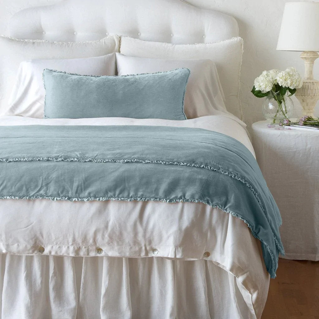 Cloud: Silk velvet shams with a petite ruffle on a white bed, stacked behind sleeping and throw pillows - view from end of bed.