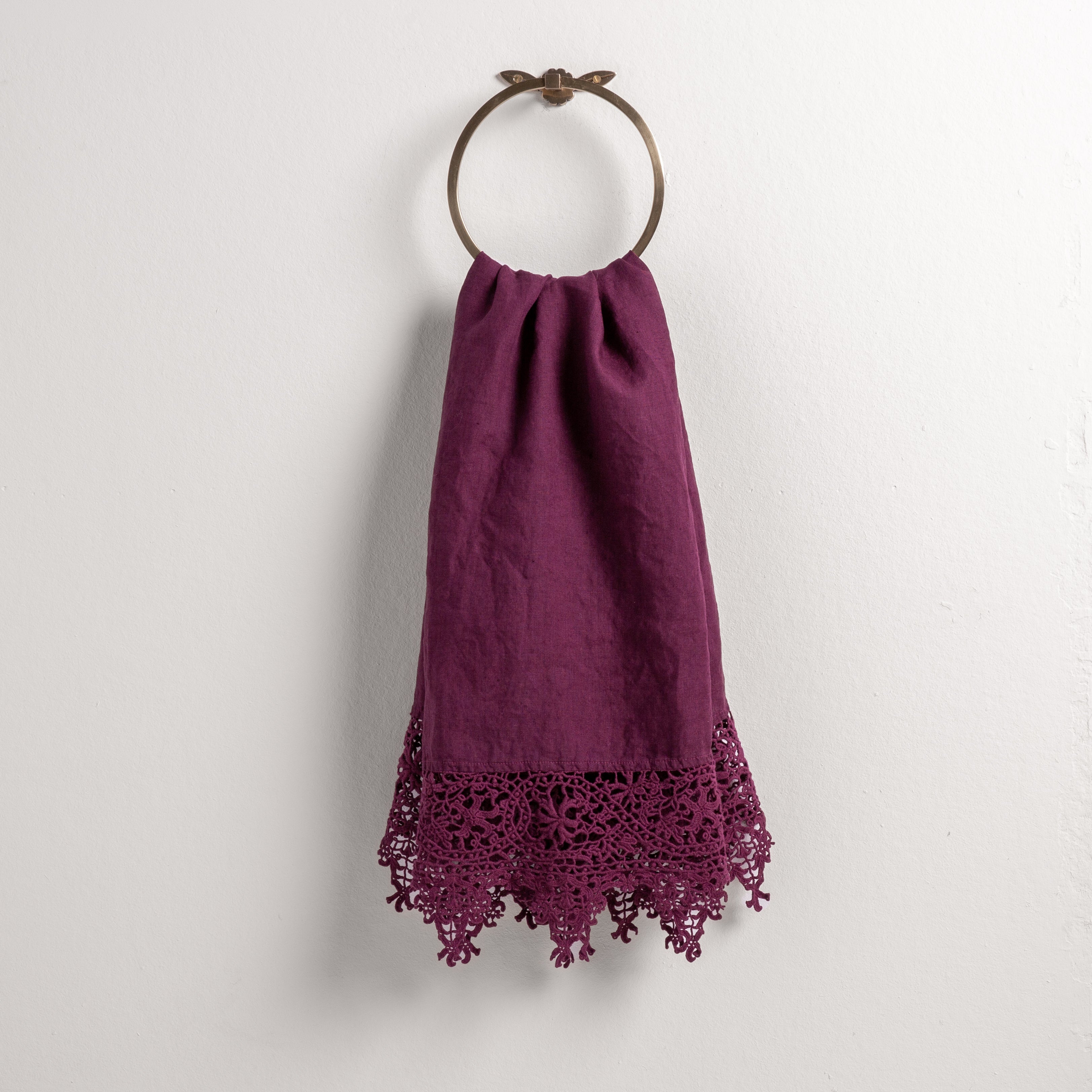 Fig: Lace trimmed linen guest towel  draped through a decorative towel ring against a plain white background.