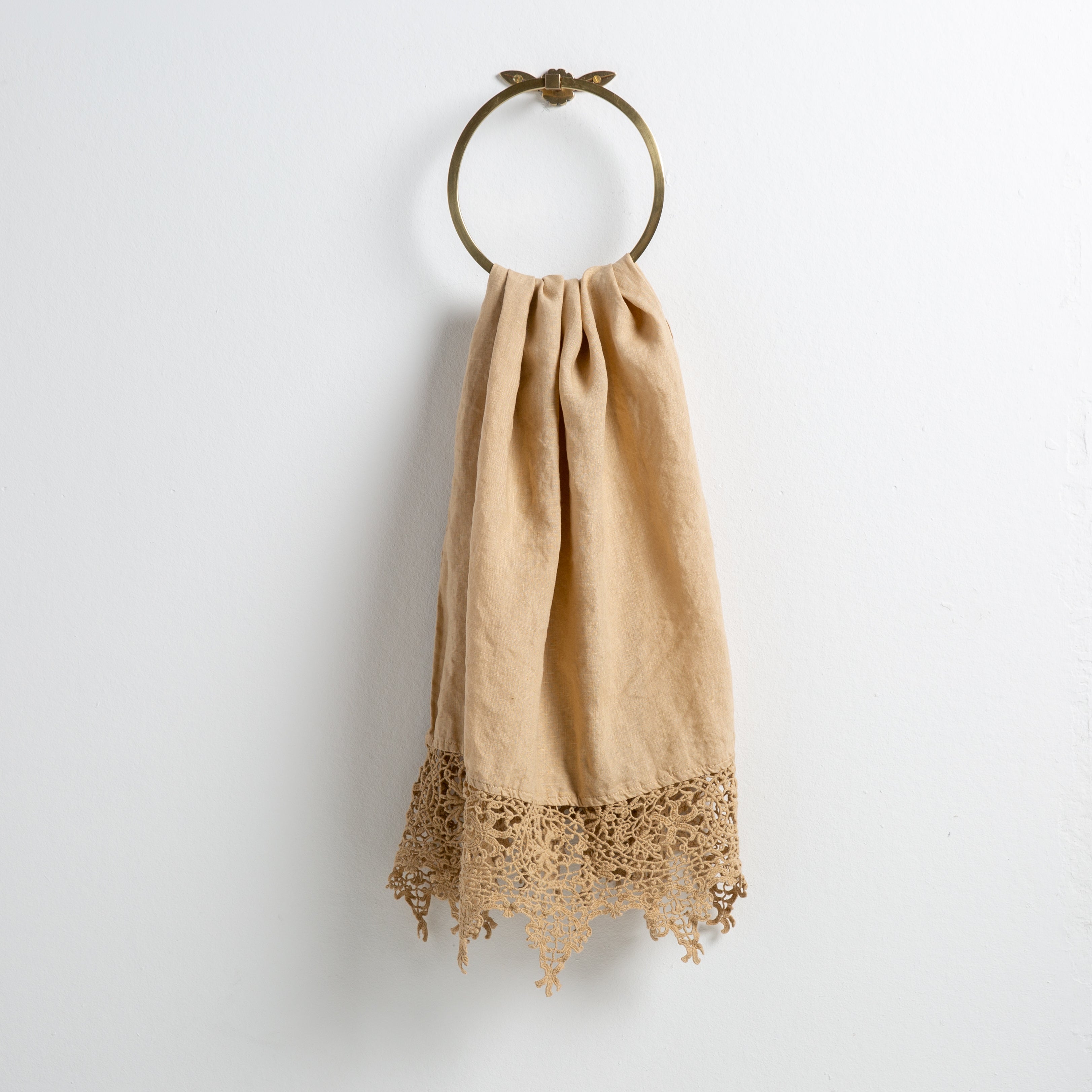 Honeycomb: Lace trimmed linen guest towel  draped through a decorative towel ring against a plain white background.