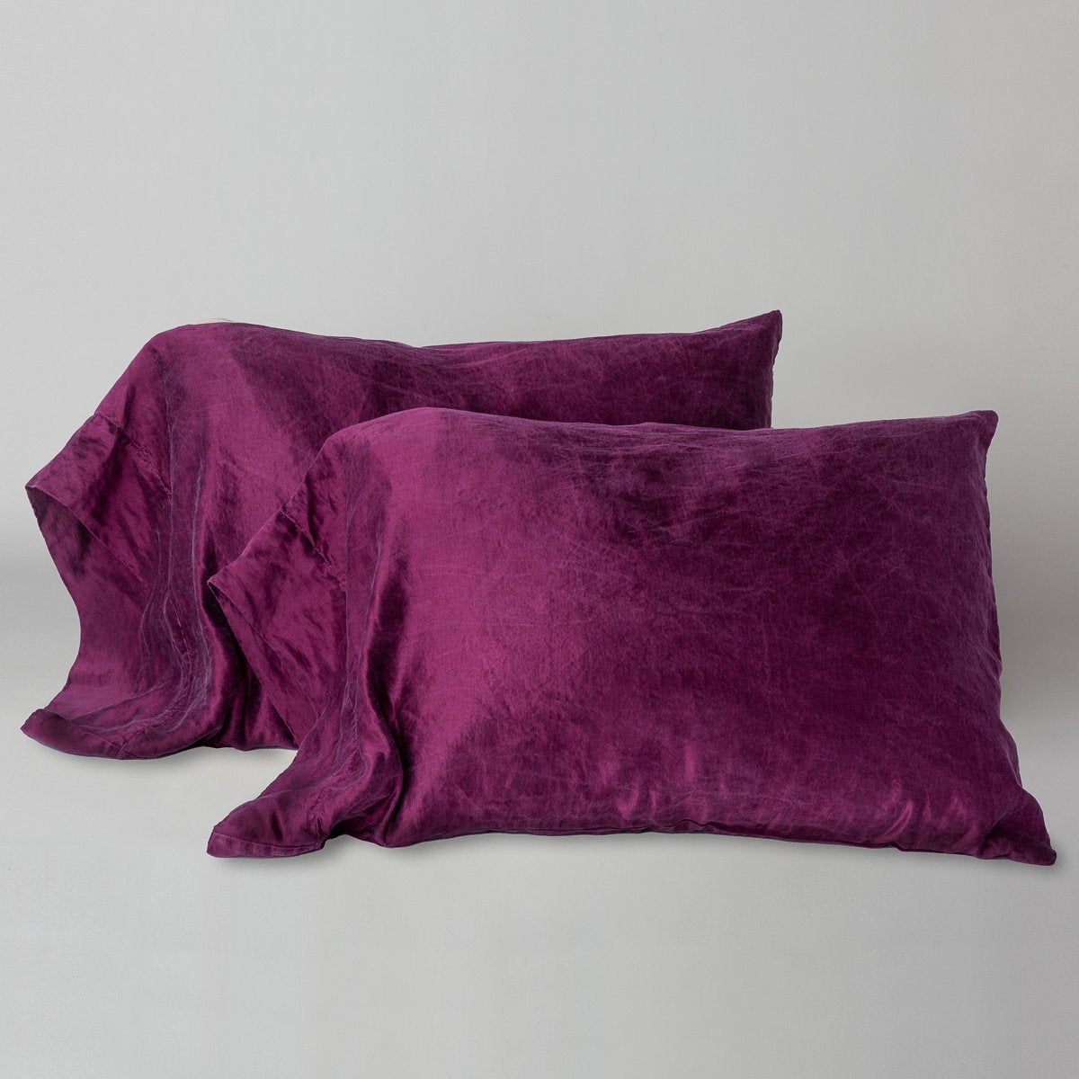 Fig: sleeping pillows leaning upright against a white wall on monochromatic sheeting - cropped three-quarter angle.