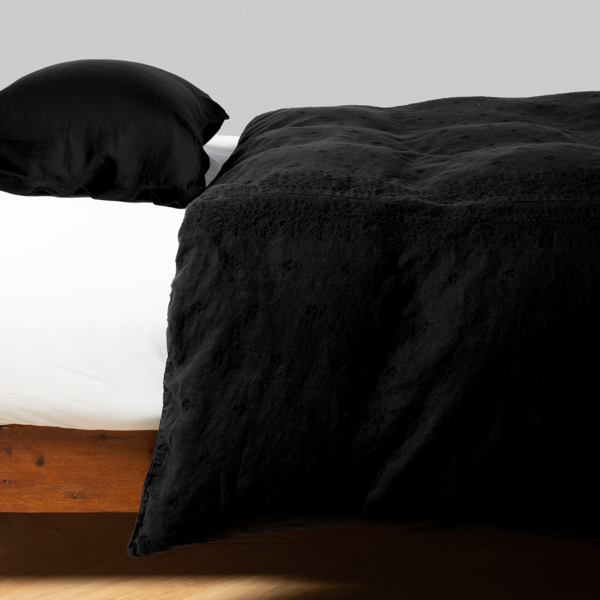 Corvino: lightly rumpled duvet cover on a monochromatic bed against a white background - side view.
